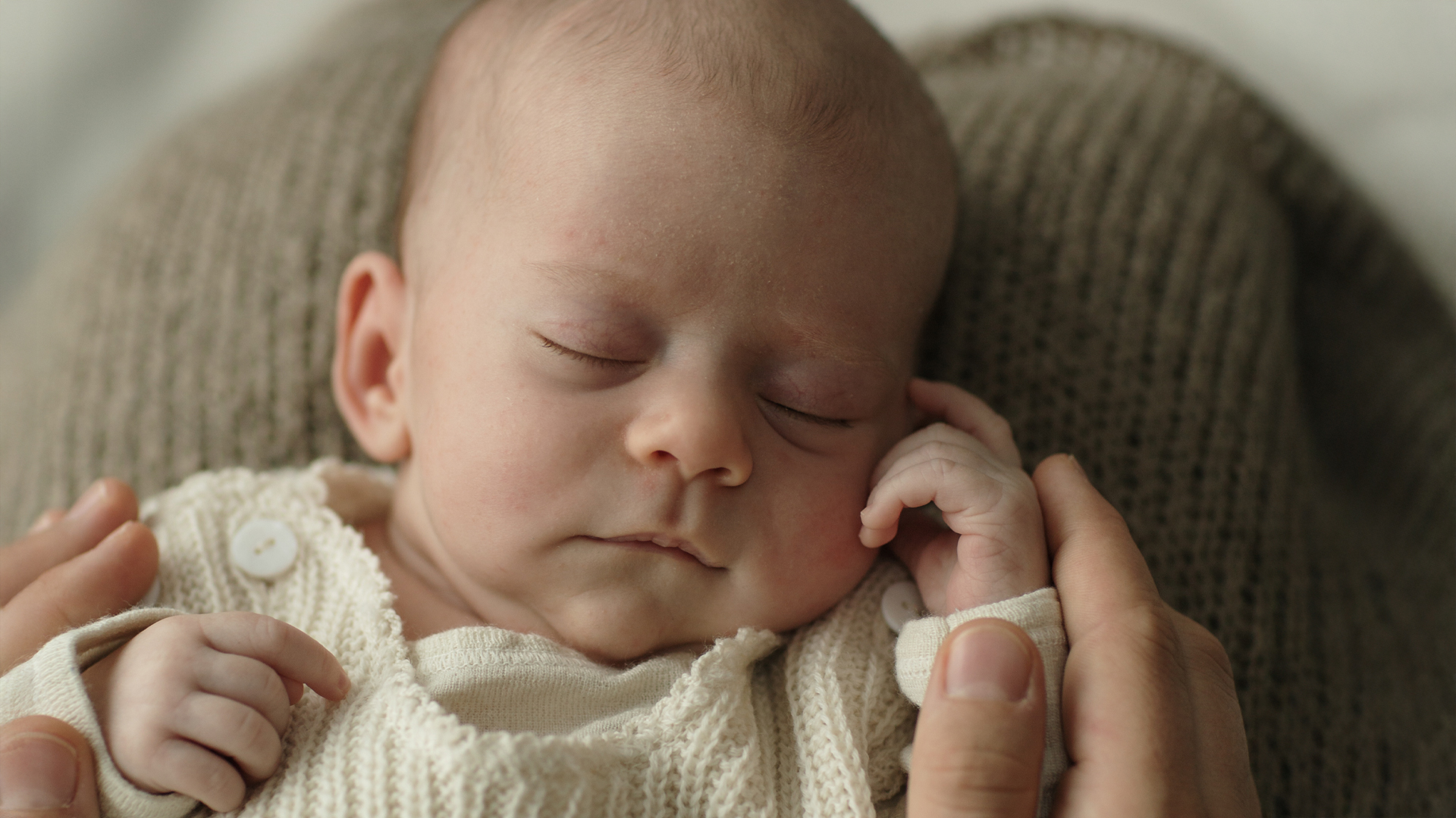 Ein Schlafendes Baby wir im Arm gehalten