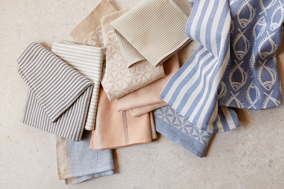 Gefaltete Heimtextilien in neutralen Farben mit Streifen und Mustern