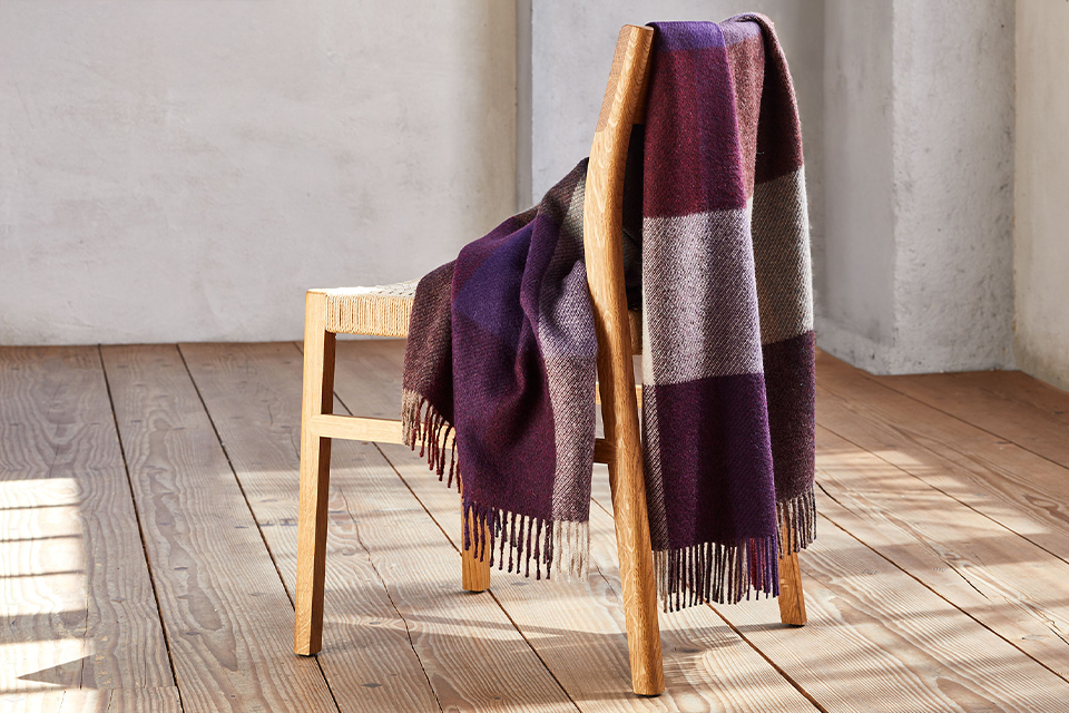 Lila Wohndecke über einen Stuhl gelegt