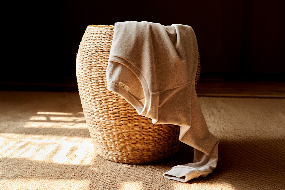 Wäschekorb mit Kleidung im warmen Sonnenlicht auf Holzboden