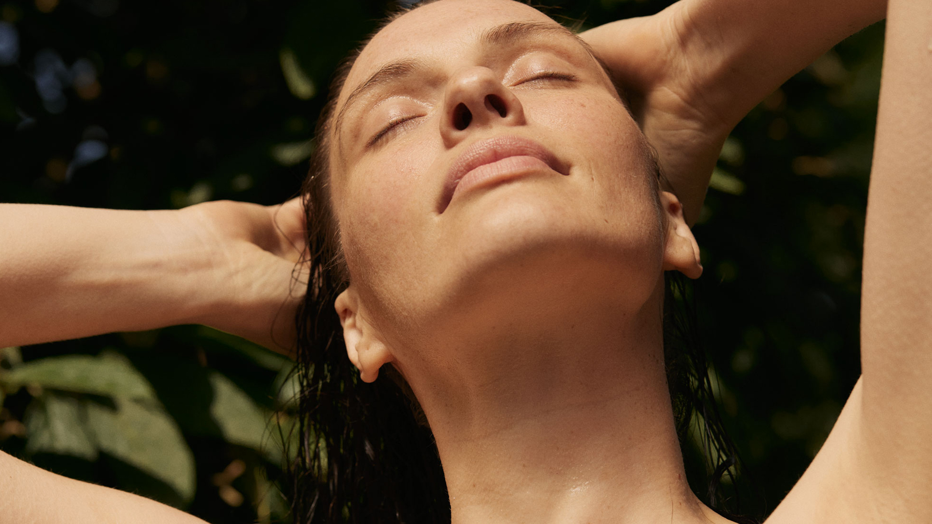 Frau genießt Sonne mit geschlossenen Augen und entspannter Haltung