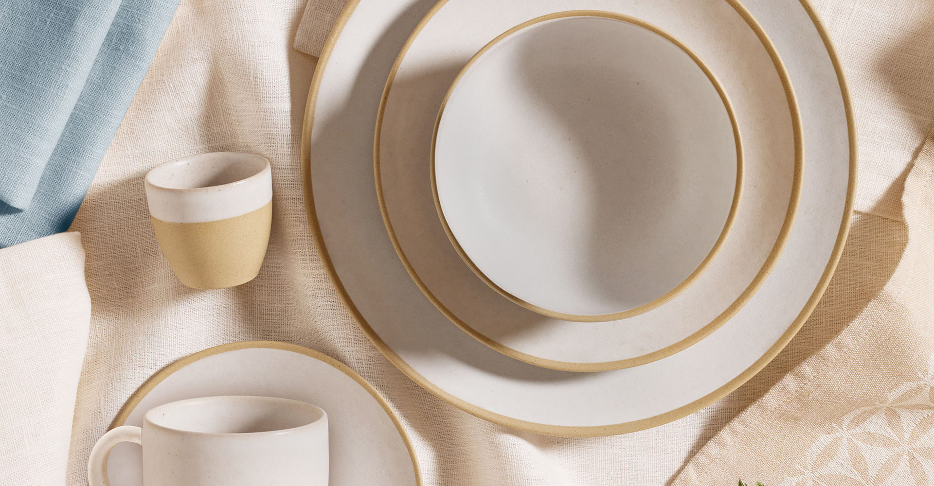 Zwei gestapelte Teller. Darauf steht eine Schüssel. Daneben liegen zwei Tassen.