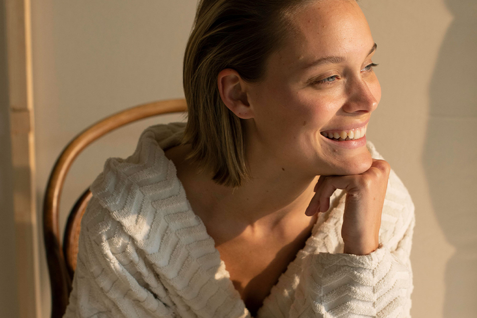 Frau lächelt im warmen Licht und wirkt entspannt und zufrieden