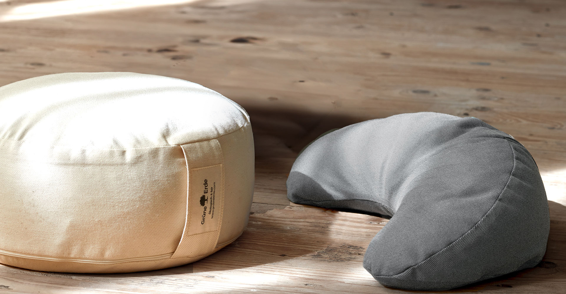 Rundes Yogakissen und Nackenkissen auf Holzboden in natürlichem Licht