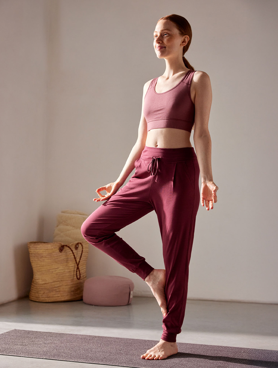 Frau macht Yoga und trägt rote Yogahose und Yogabra