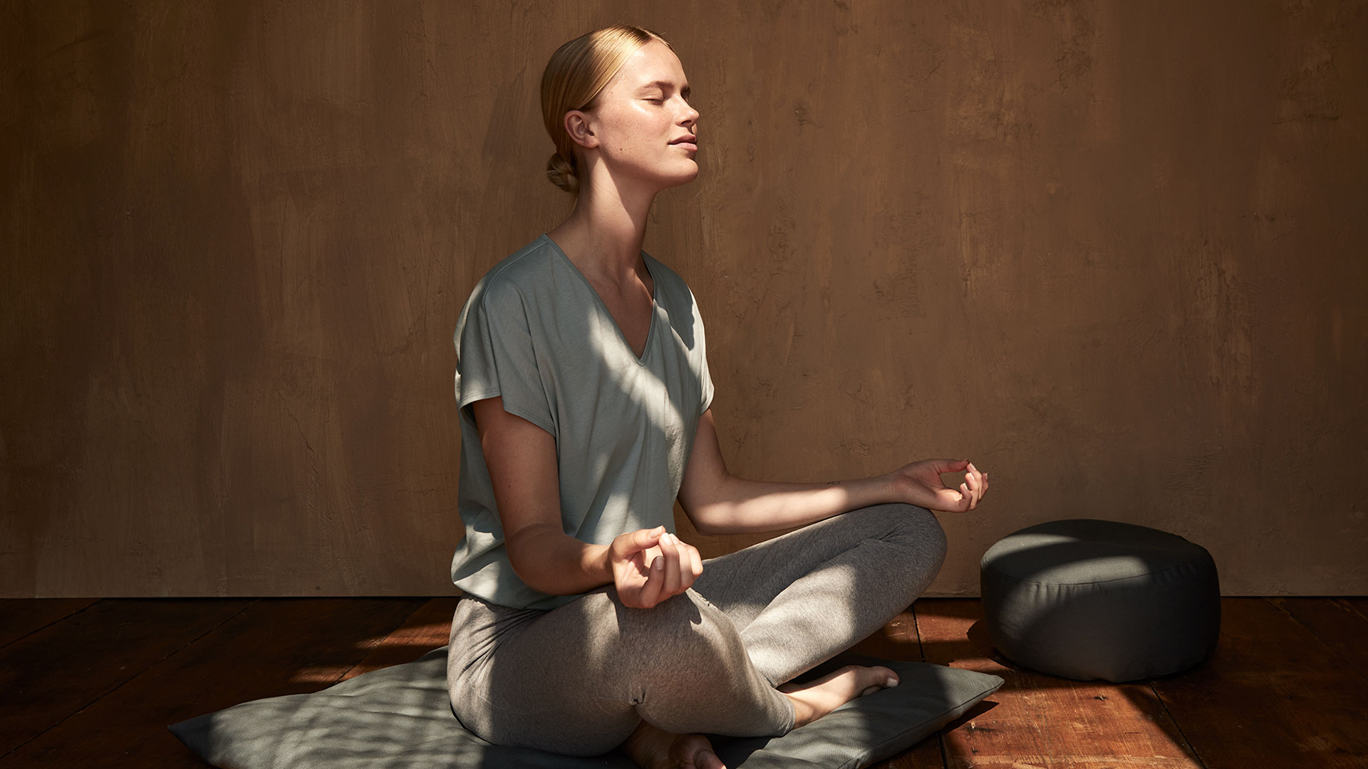 Frau meditiert ruhig in warmem Raum mit geschlossenen Augen