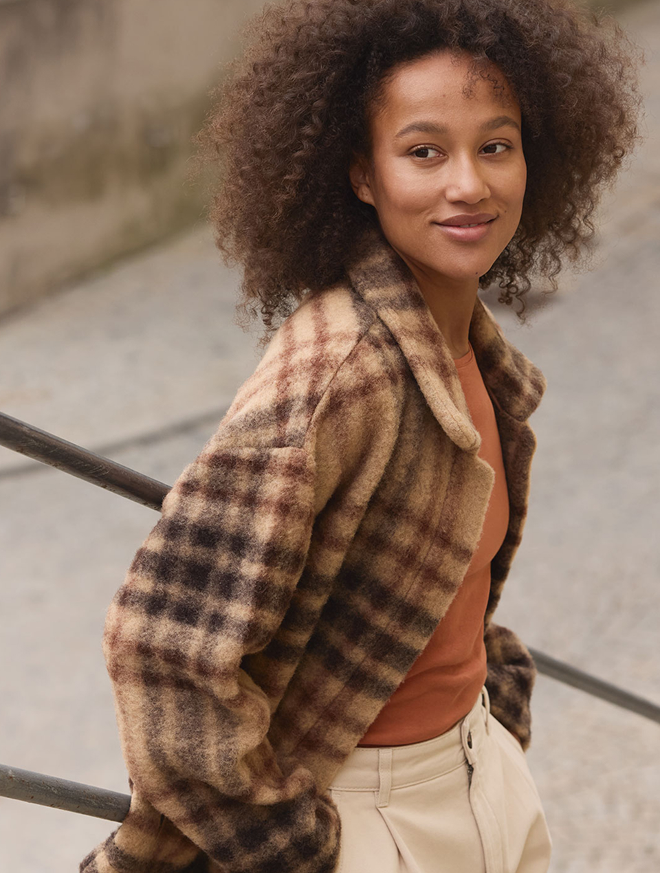 Frau mit dunklen Locken trägt eine karierte Wolljacke