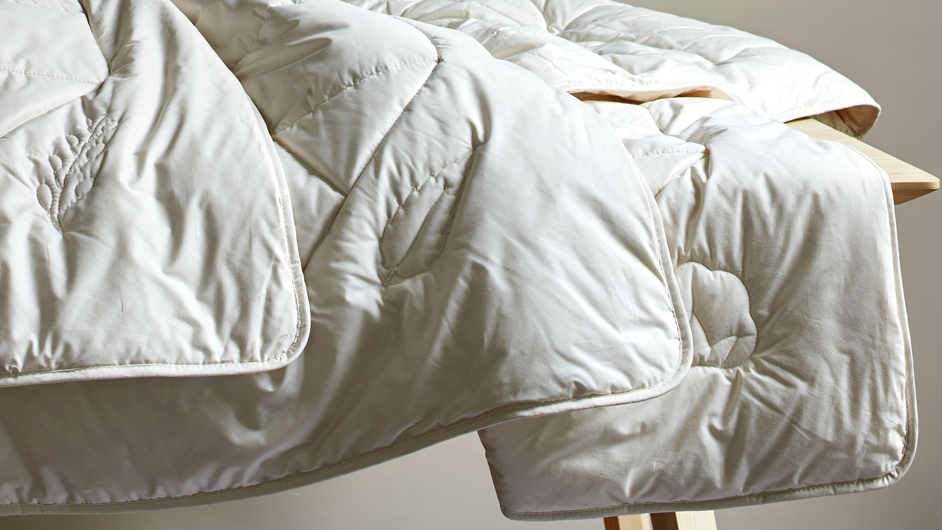 Bettdecken übereinander liegend auf einer dekorativen Holzbank