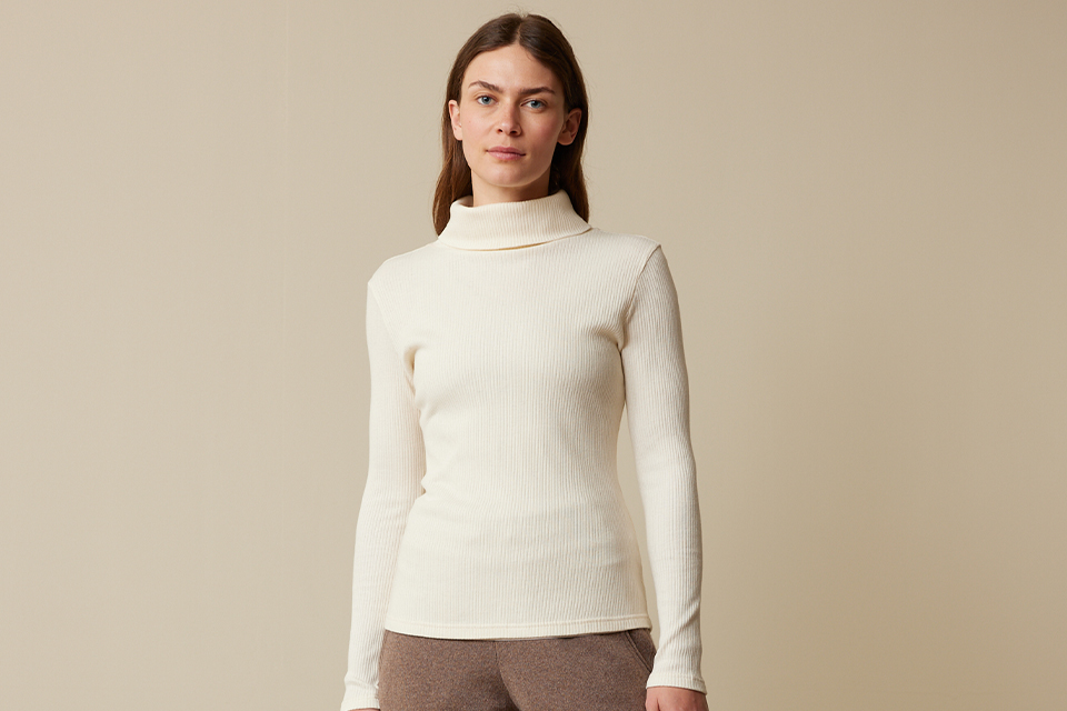 Frau in naturfarbenem Shirt vor weißem Hintergrund