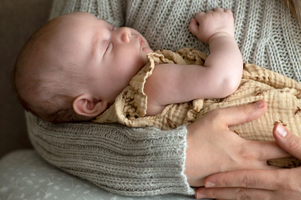 Schlafendes Baby im Arm der Mutter liegend