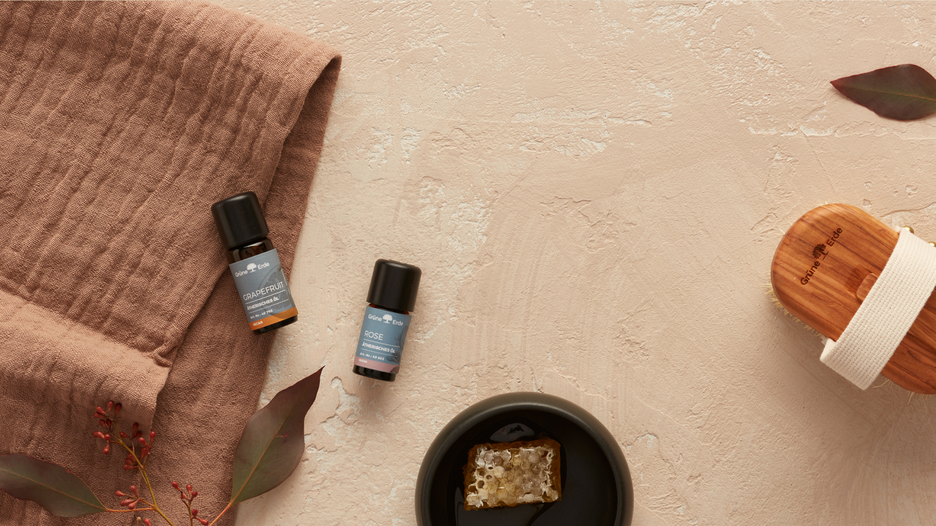 Ätherische Öle auf Stoff mit Honig und Blättern stilvoll arrangiert