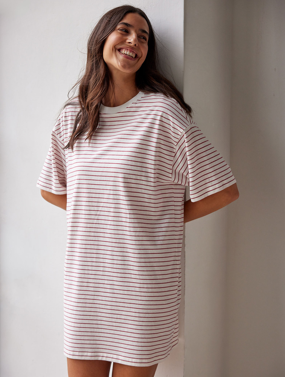 Frau trägt gestreiftes Schlafshirt und lehnt an einer Wand