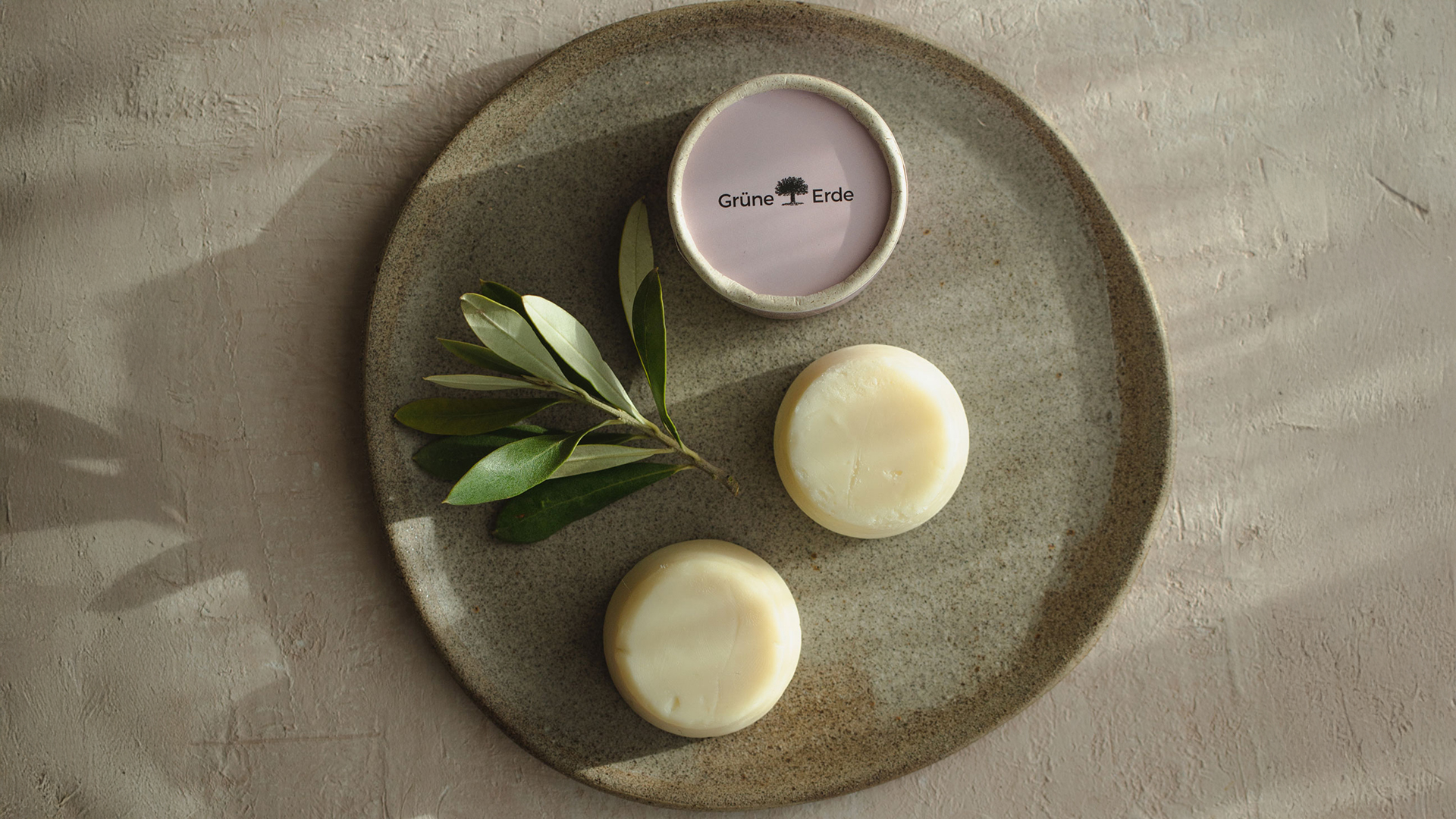 Hand und Fußpflege auf einem Steinteller neben einem dekorativen Zweig