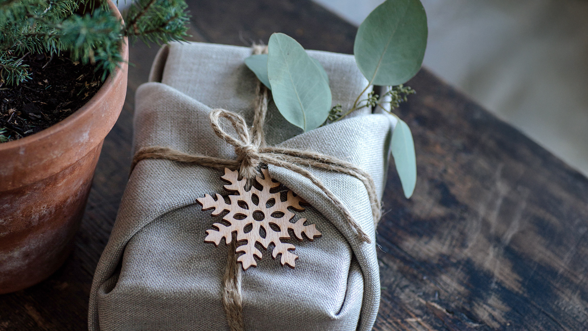 Mit einem Tuch verpacktes Geschenk neben einem Blumentopf aus Ton