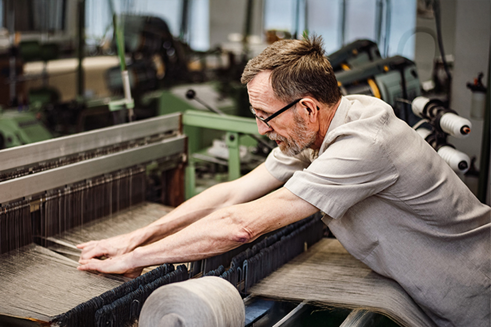 Mann betätigt eine Webmaschine