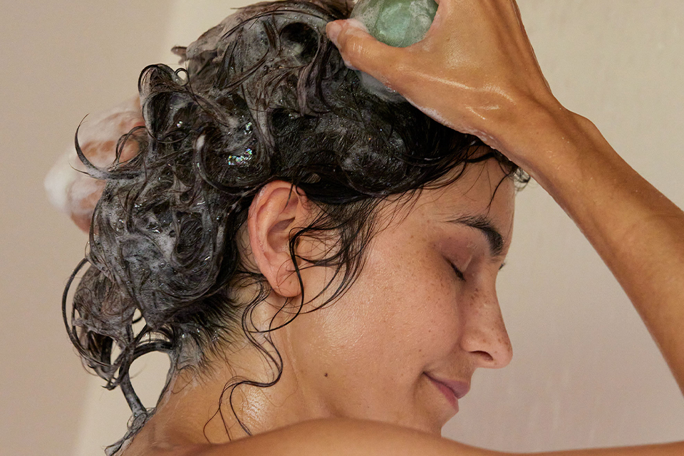 Frau wäscht ihre Haare und genießt entspannende Pflegeroutine