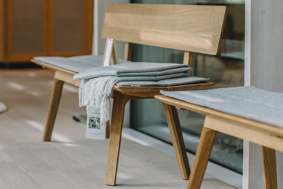 Holzbänke mit grauen Sitzpolstern und Wohndecke