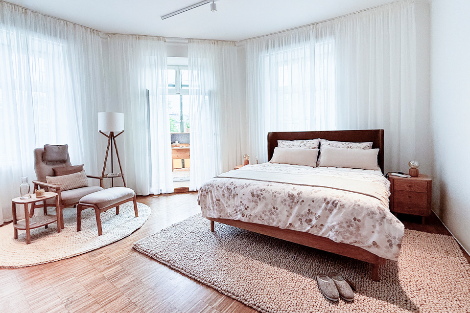 Holzbett mit Nachtkästchen und Polstersessel mit Stehlampe und Tischchen in einem Schlafzimmer