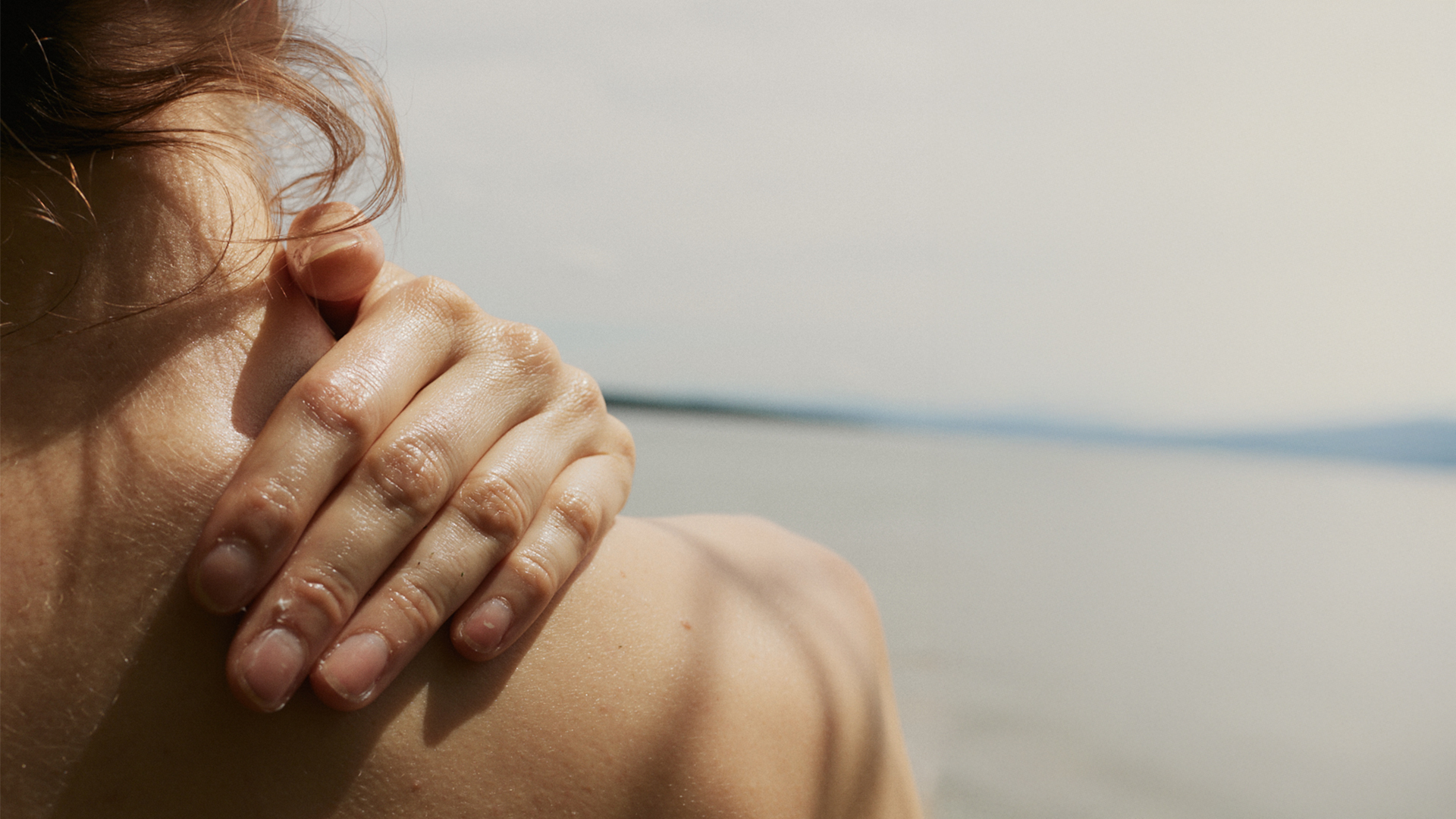 Frau berührt ihre Schulter mit der Hand