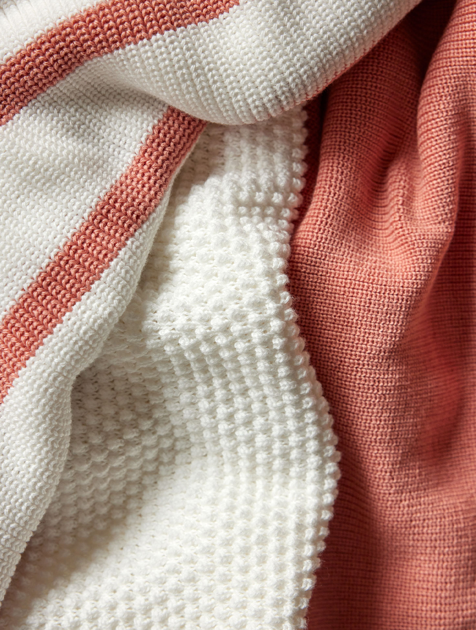 Nahaufnahme von drei Pulloverstoffen in Weiß und Apricot