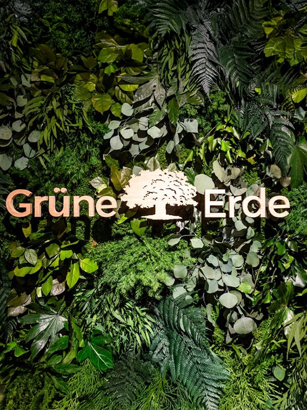 Grüne Pflanzenwand mit Logo und natürlichem Markenauftritt