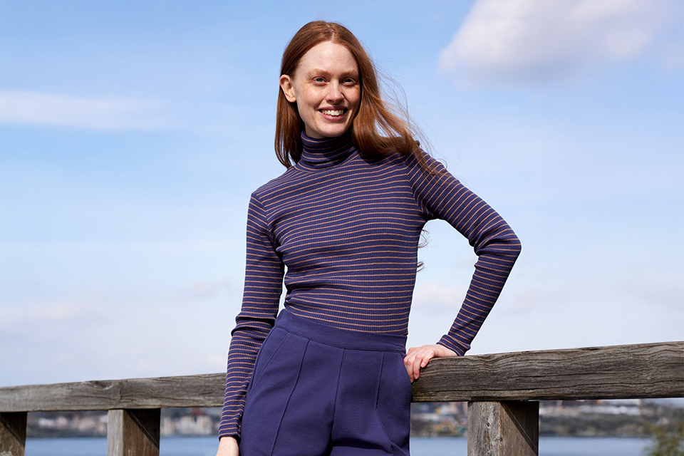 Frau im lila Oberteil posiert selbstbewusst im Freien