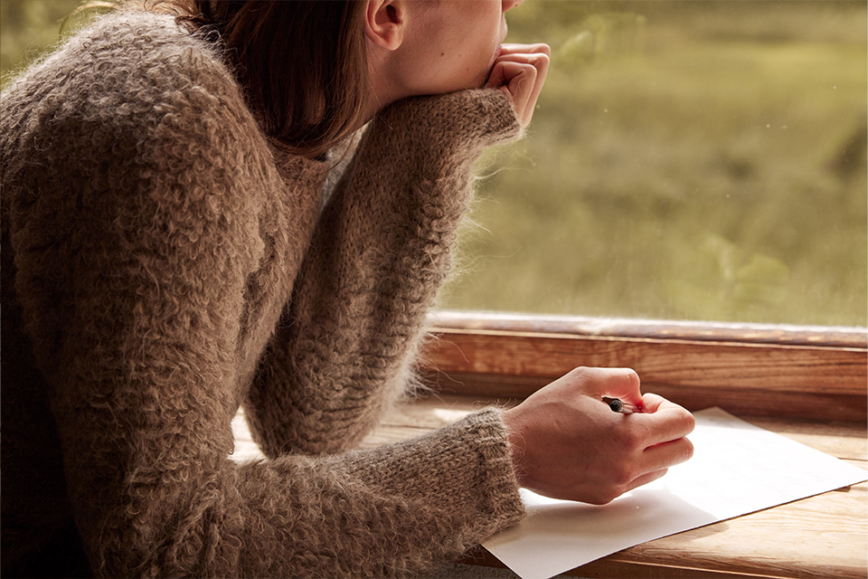 Person schreibt achtsam in Notizbuch bei warmem Licht