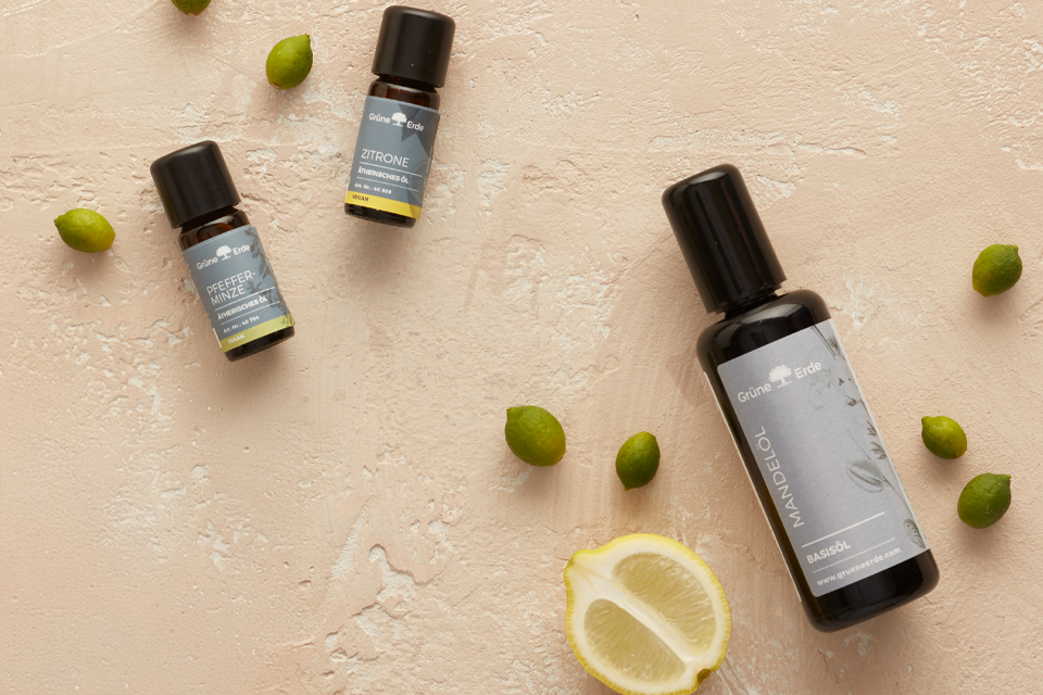 Basisöl und ätherische Öle mit Knospen und einer Zitrone dekorativ angeordnet