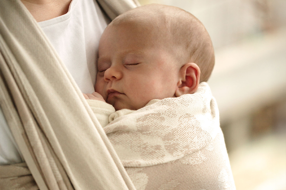 Ein Baby schläft im Tragetuch