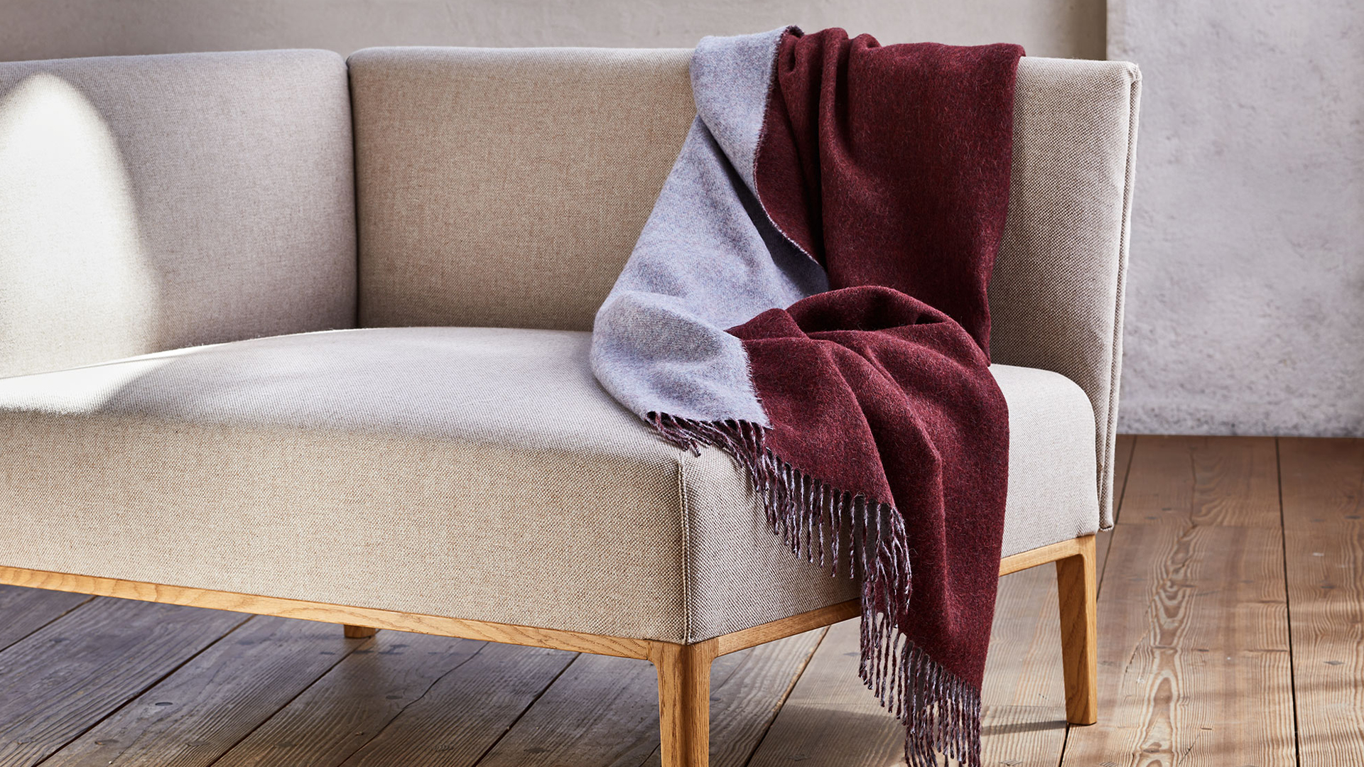 Rot-graue Wohndecke über eine Sofalehne gelegt