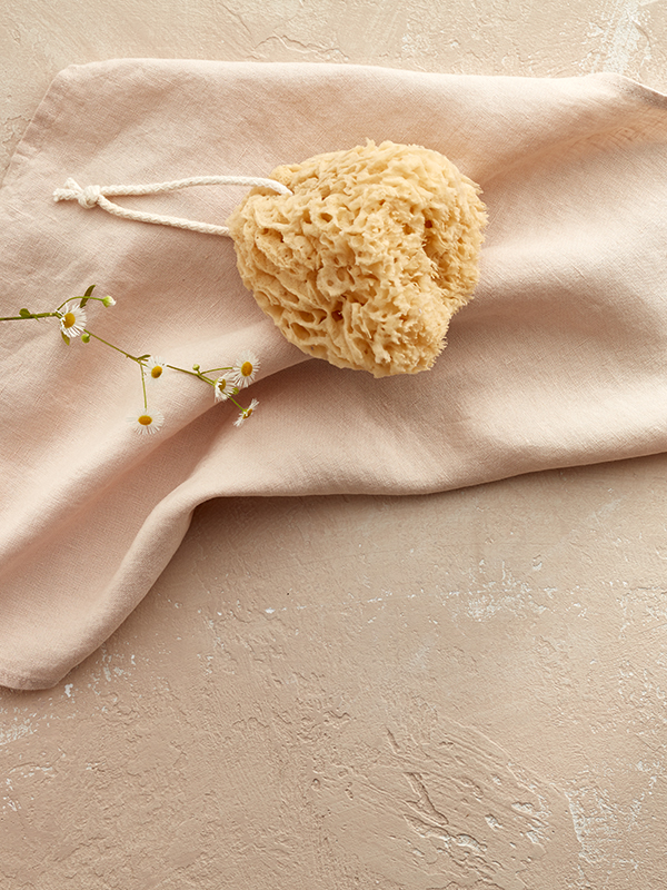 Ein Badeschwamm liegt auf einem hellen tuch