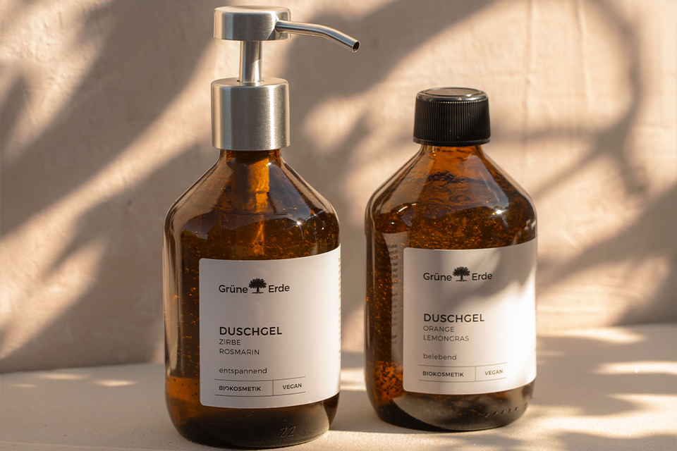 Zwei Duschgels in Glasflaschen mit einem Metallspender und einem aus Plastik