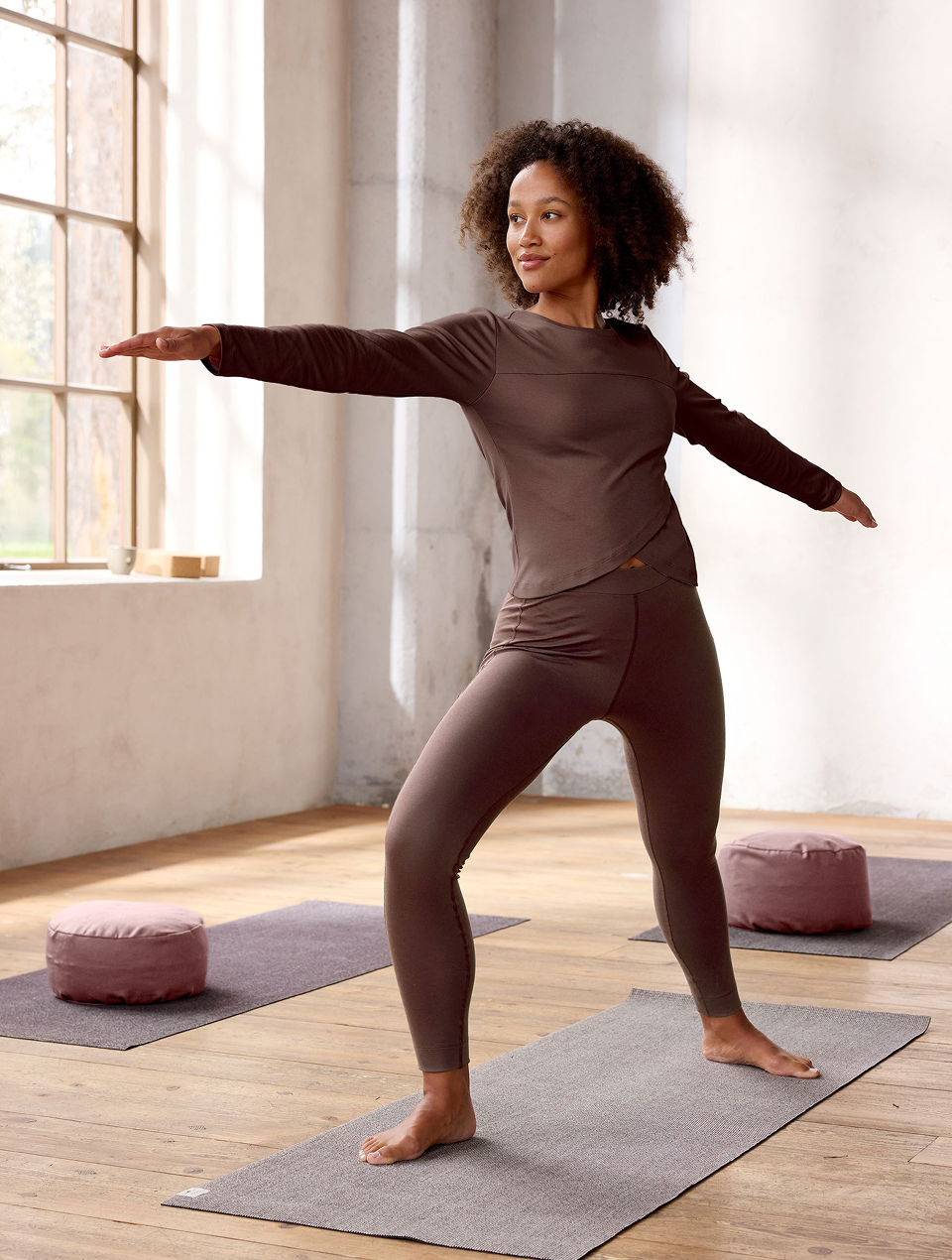 Frau macht Yoga und trägt eine braune Leggings und ein braunes Shirt