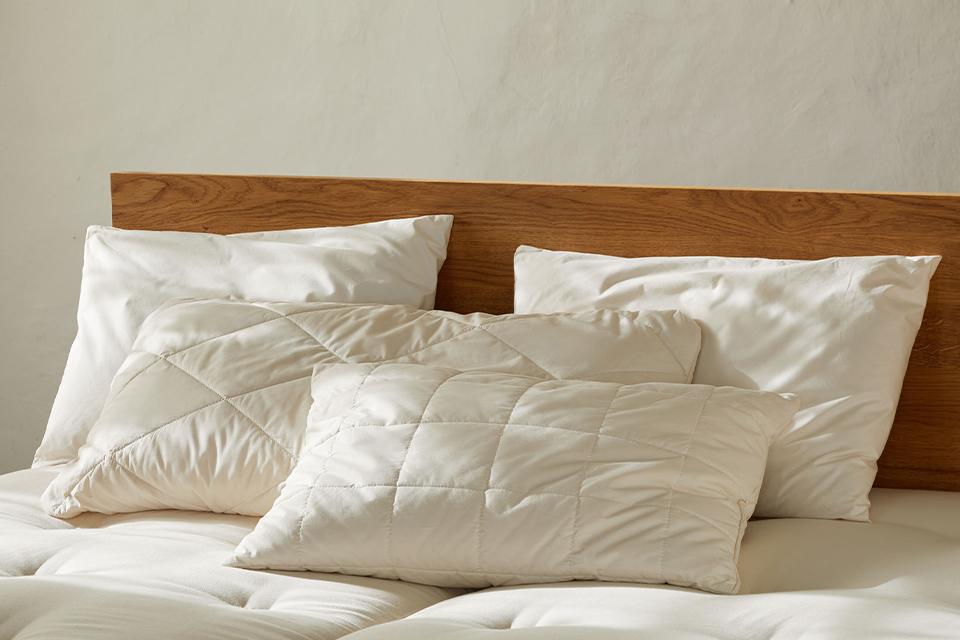 Vier verschiedene Schlafkissen auf einem Massivholzbett mit Naturmatratzen