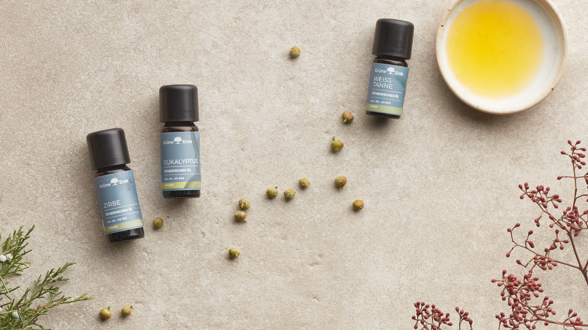 Ätherische Öle und eine Schale mit Öl nebeneinander angeordnet