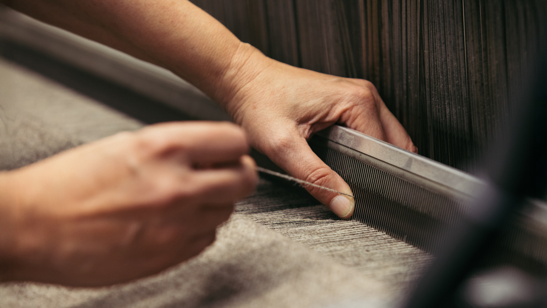 Hände betätigen eine Webmaschine