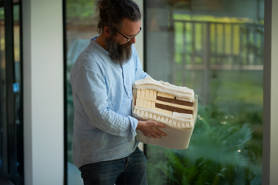 Mann hält den Querschnitt einer Matratze in den Händen