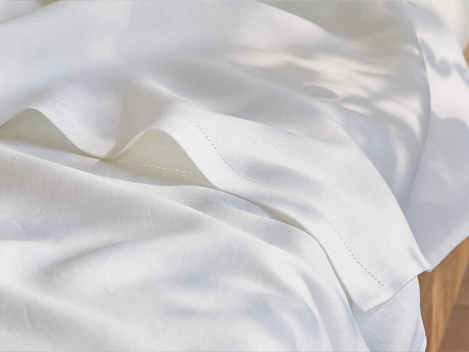 Weißes Spannleintuch auf einem Bett drapiert