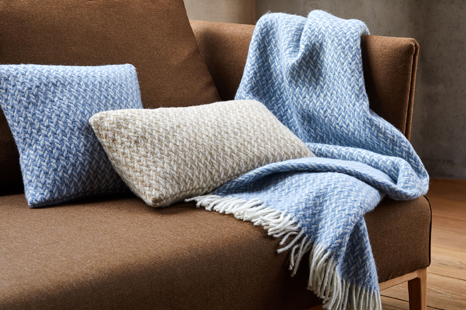 Zierkissen und Wohndecke auf einem braunen Sofa liegend