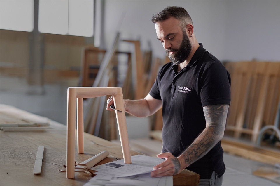 Mann arbeitet konzentriert an Holzrahmen in heller Werkstatt