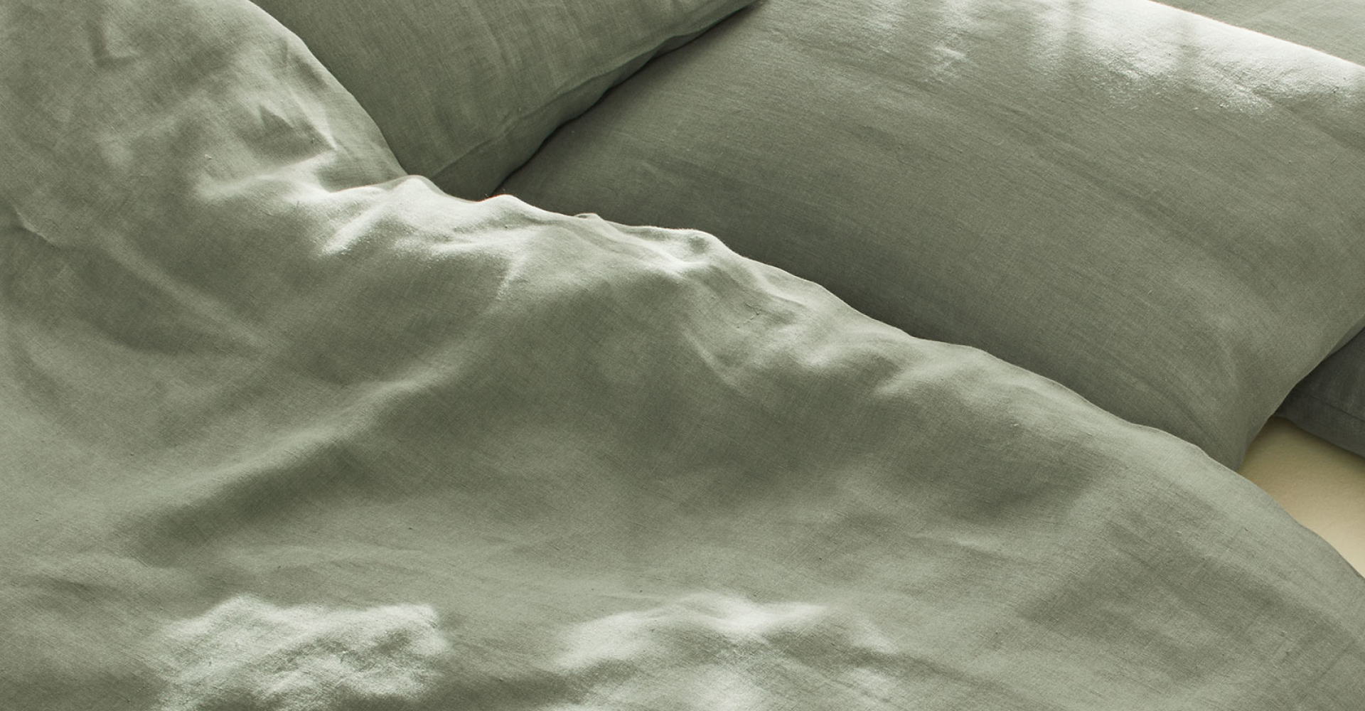 Grüne Bettwäsche auf einem Bett drapiert