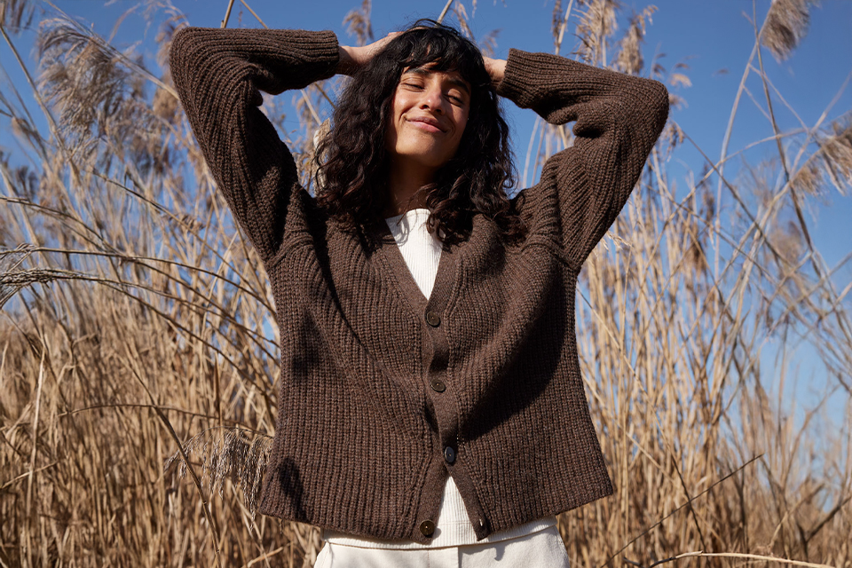 Frau im braunen Pullover genießt Sonne im Freien