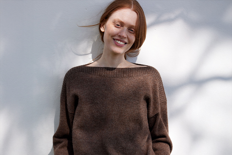 Lächelnde Frau im braunen Pullover im weichen Licht