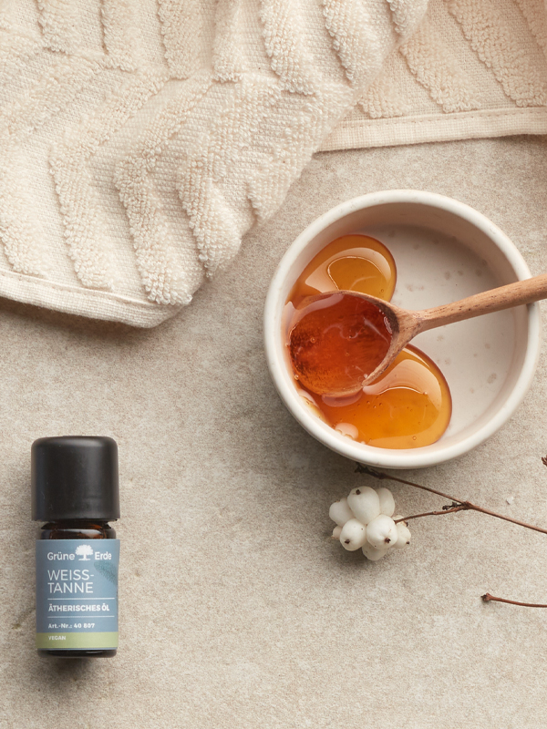 Ätherische Öle neben einer Schale mit Honig