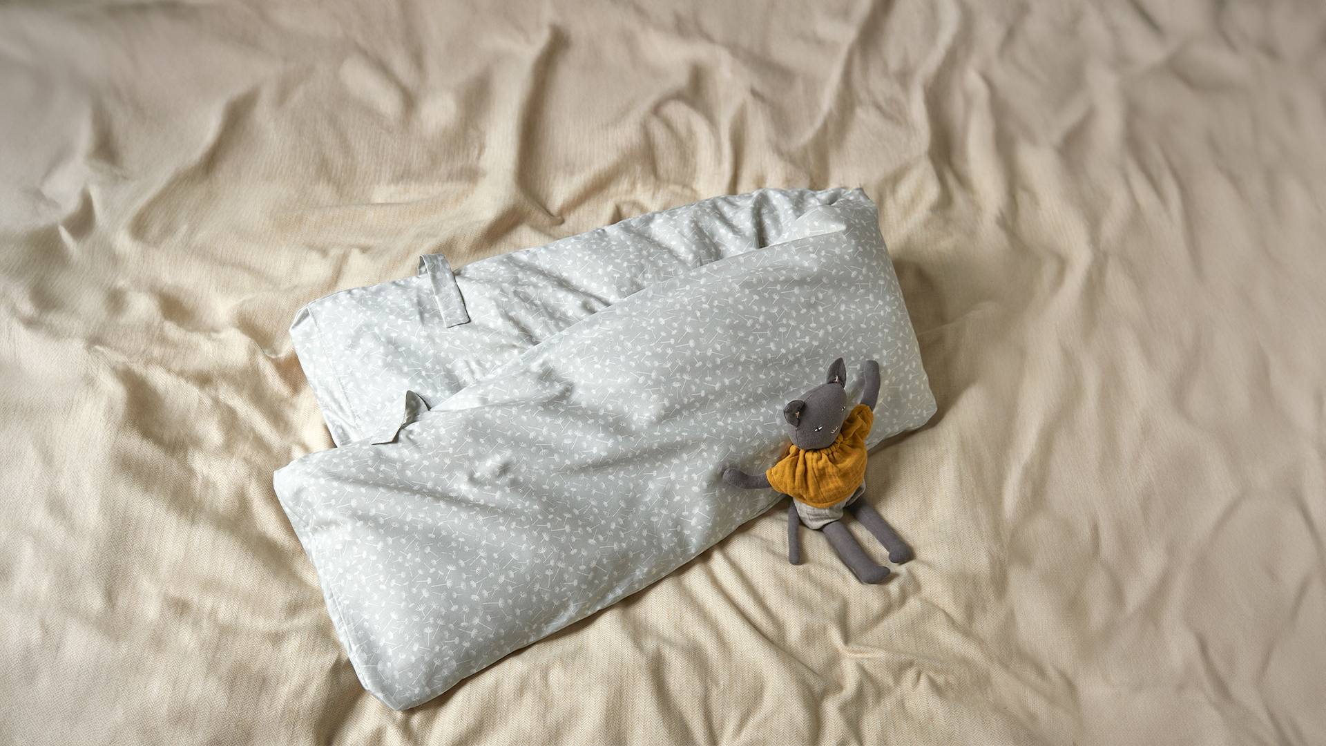 Still- und Seitenschläferkissen mit blaugrauem Überzug liegt auf beigem Untergrund